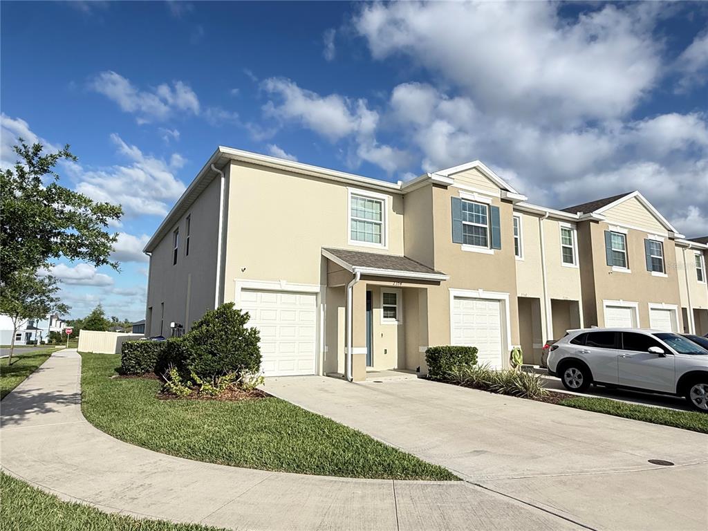 A two-story townhouse with a beige stucco exterior, a concrete driveway, and a garage — 2354 TAY WES DRIVE, ST CLOUD, FL