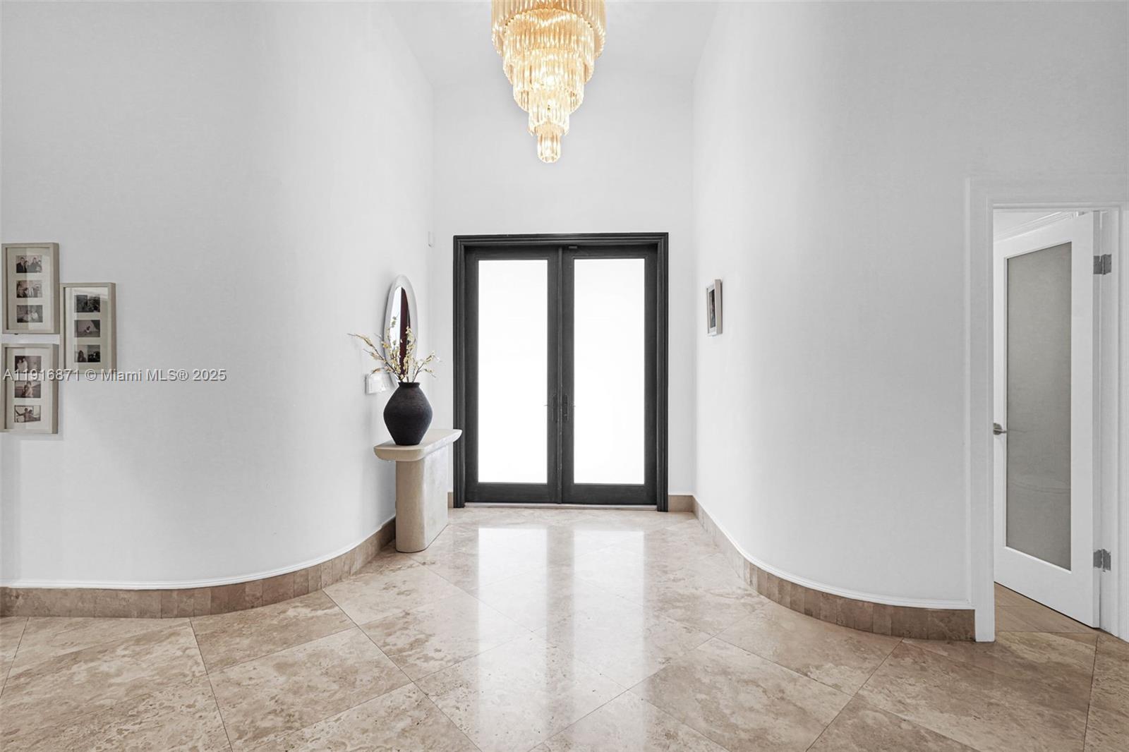 A bright entryway features a crystal chandelier, tiled floors, and a dark-framed double door — 145 Bal Bay Dr, Bal Harbour FL 33154, BAL HARBOUR, FL