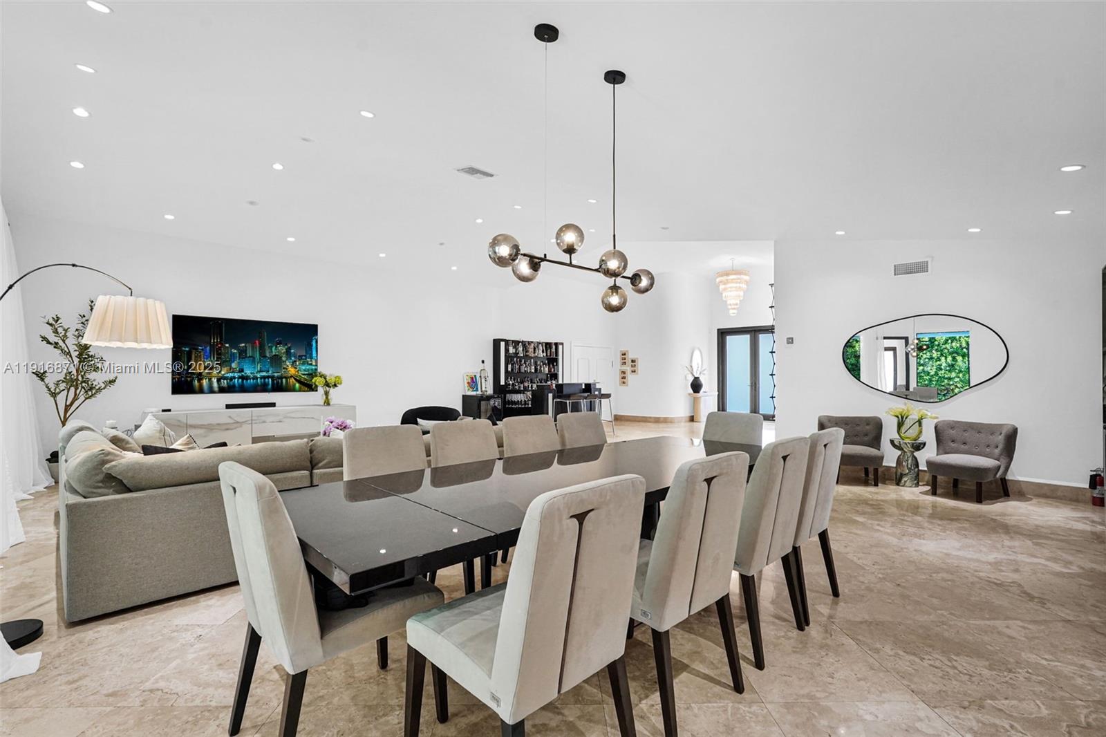 A modern dining area features a dark table, upholstered chairs, and a contemporary globe chandelier — 145 Bal Bay Dr, Bal Harbour FL 33154, BAL HARBOUR, FL