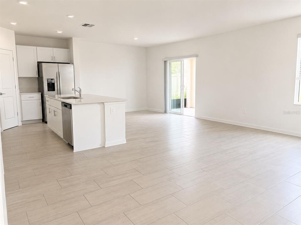 A kitchen with white cabinets and an island opens into a spacious living area — 4011 NORTHERN KEY DRIVE, PLANT CITY, FL