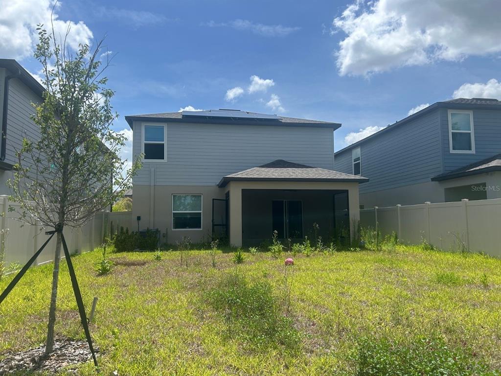 The rear exterior of a two-story house features a covered patio and a fenced yard — 4011 NORTHERN KEY DRIVE, PLANT CITY, FL