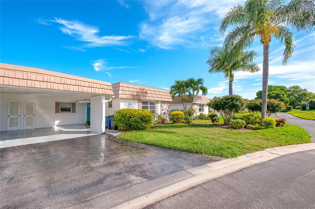 A sunroom with wood-look flooring and large windows overlooking a lake and green landscape — 2126 RIVERBLUFF PARKWAY UNIT V323, SARASOTA, FL