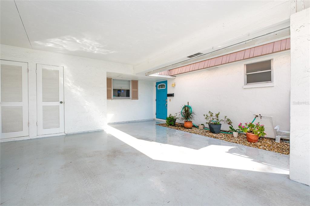 A sunroom with wood-look flooring overlooks a canal, connecting to an open-concept kitchen — 2126 RIVERBLUFF PARKWAY UNIT V323, SARASOTA, FL