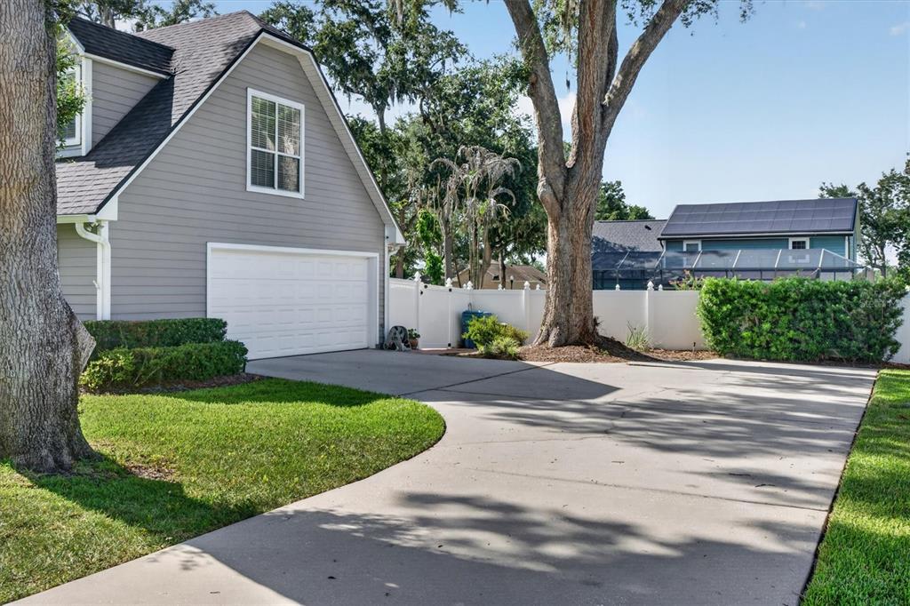 A gray house with a white garage door sits next to a large tree and driveway — 434 VALLEY VIEW DRIVE, WINTER GARDEN, FL