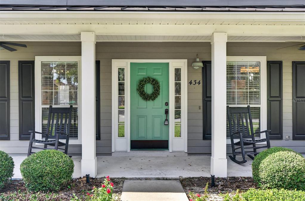 A front porch features a teal door with a wreath, two rocking chairs, and landscaping — 434 VALLEY VIEW DRIVE, WINTER GARDEN, FL