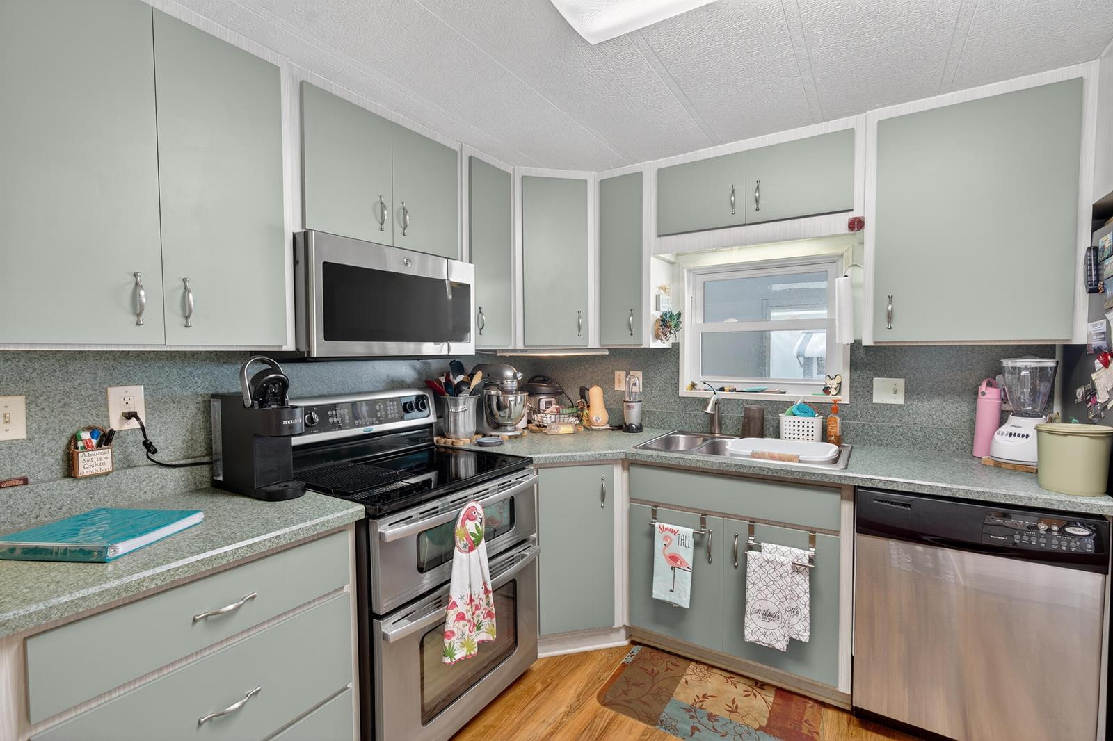 A kitchen features light green cabinets, stainless steel appliances, and a double-basin sink — 1520 St Thomas Avenue, Sebring FL 33870, SEBRING, FL