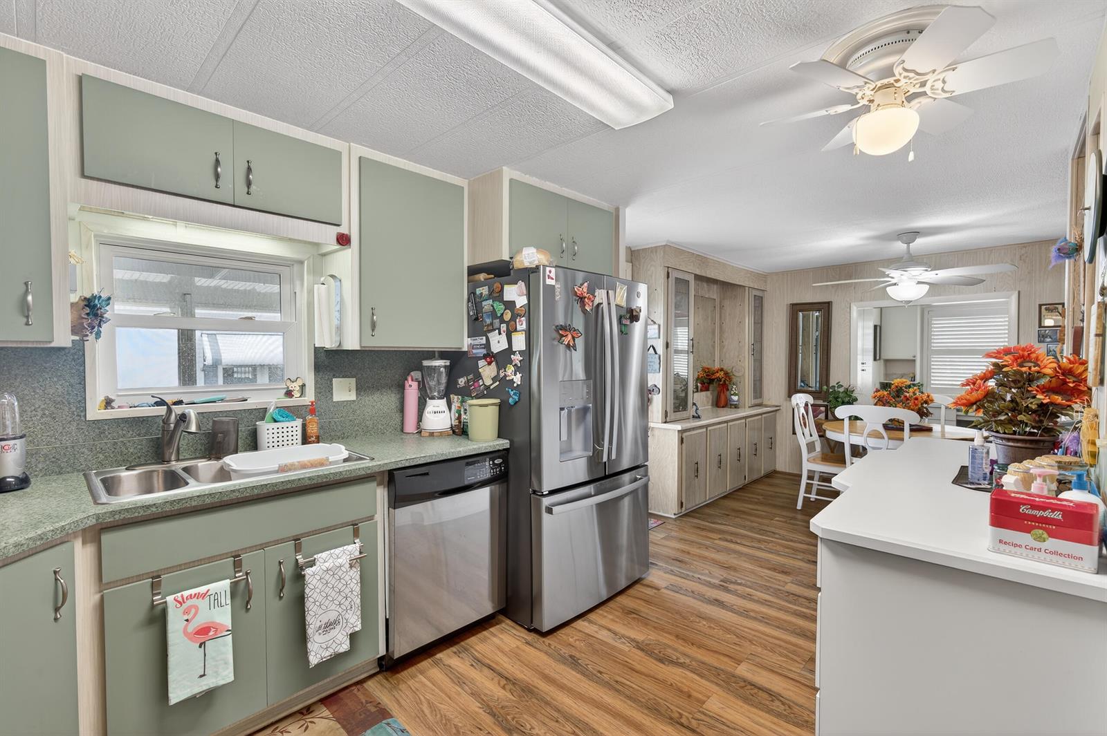 A kitchen with sage green cabinets, stainless steel appliances, and wood-look flooring — 1520 St Thomas Avenue, Sebring FL 33870, SEBRING, FL
