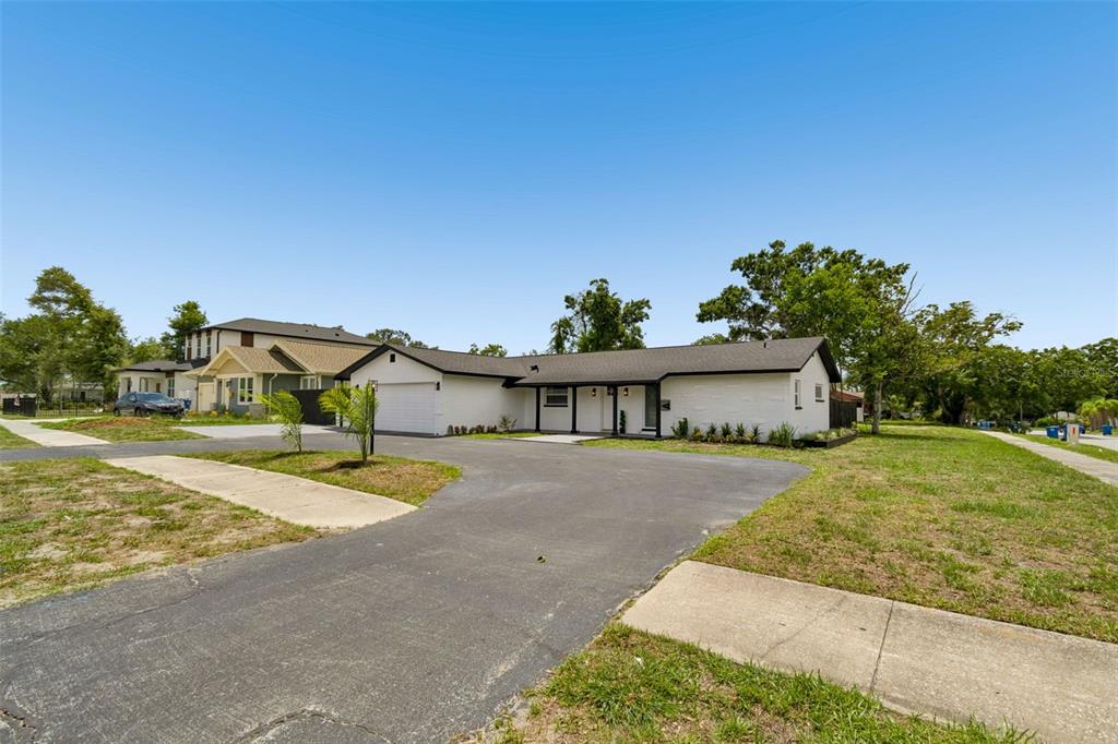 A white single-story house with a black roof and a large asphalt driveway — 1530 49TH STREET N, ST PETERSBURG, FL