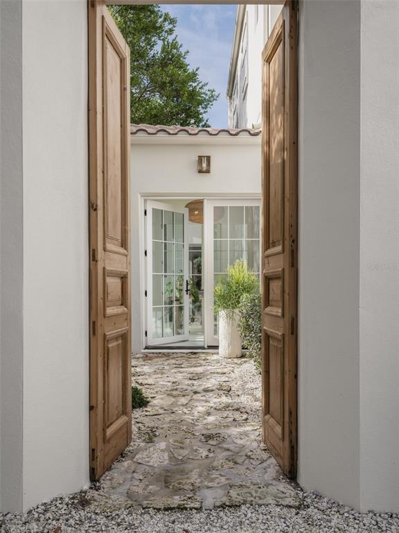 A bright entryway features white-framed windows, a rustic wooden console table, and a woven pendant light — 1150 VIA SALERNO, WINTER PARK, FL