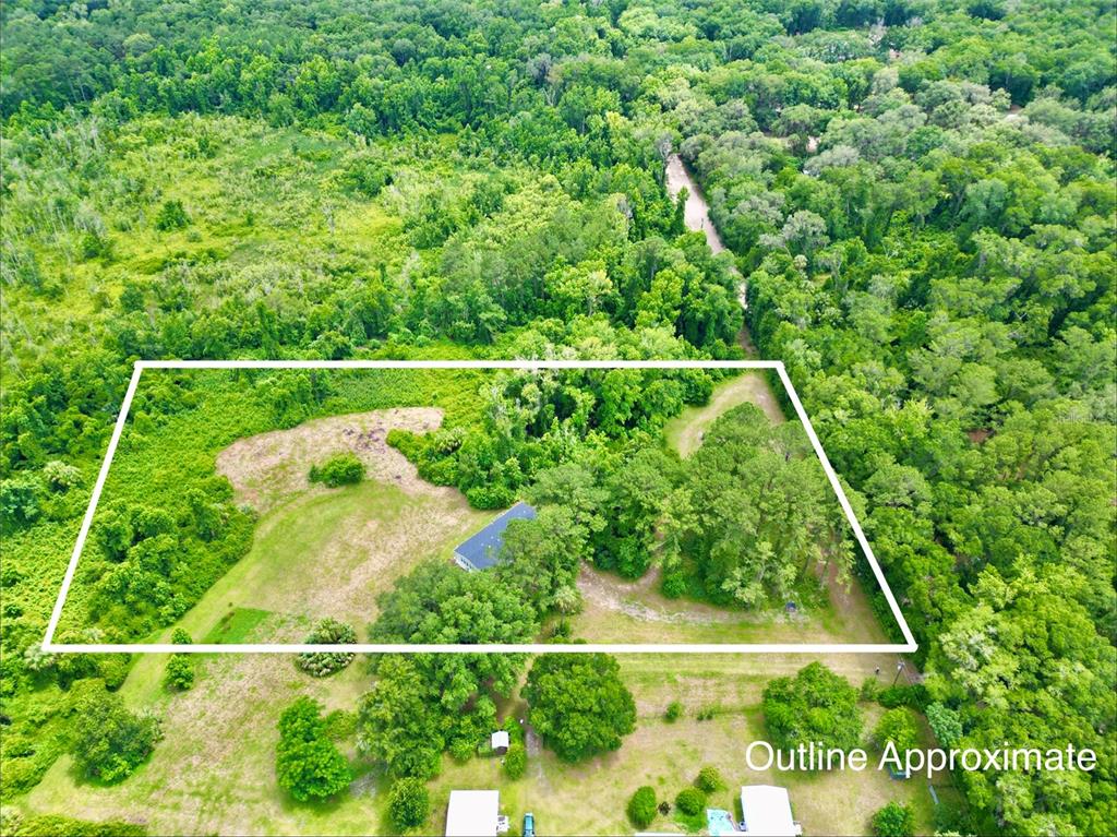 An aerial view shows a house situated on a large, partially wooded lot — 122 TANNER ROAD, FLORAHOME, FL