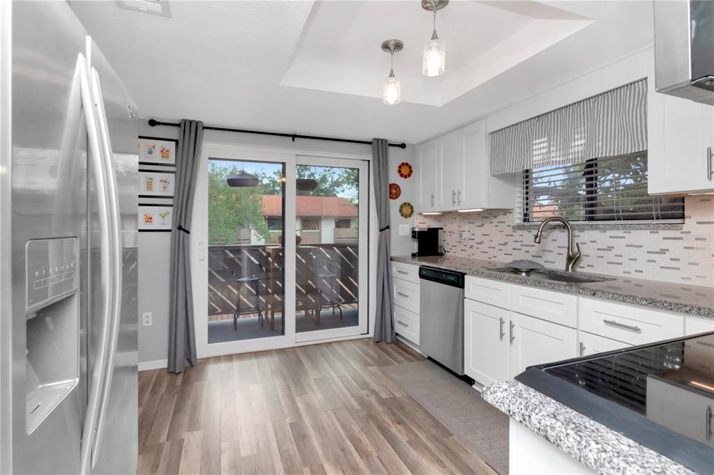 A kitchen with white cabinets, granite countertops, stainless steel appliances, and a sliding glass door — 2363 FLANDERS WAY UNIT C, SAFETY HARBOR, FL