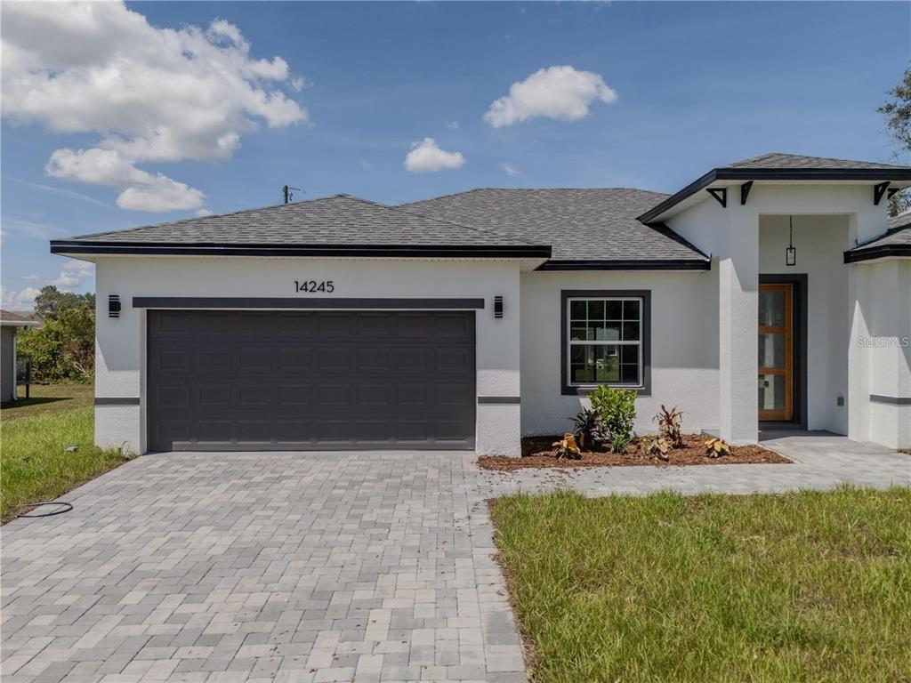 A single-story house with a white stucco exterior, dark gray roof, and a paved driveway — 14245 SW 28TH COURT, OCALA, FL