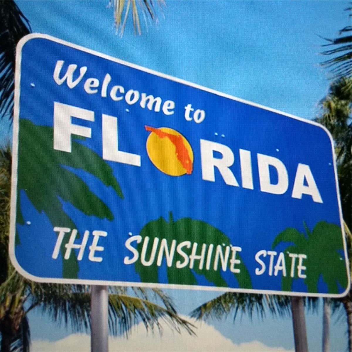 A blue road sign welcomes visitors to Florida, the Sunshine State, with palm trees in background — 111 SE 7th Street, Pompano Beach FL 33060, POMPANO BEACH, FL
