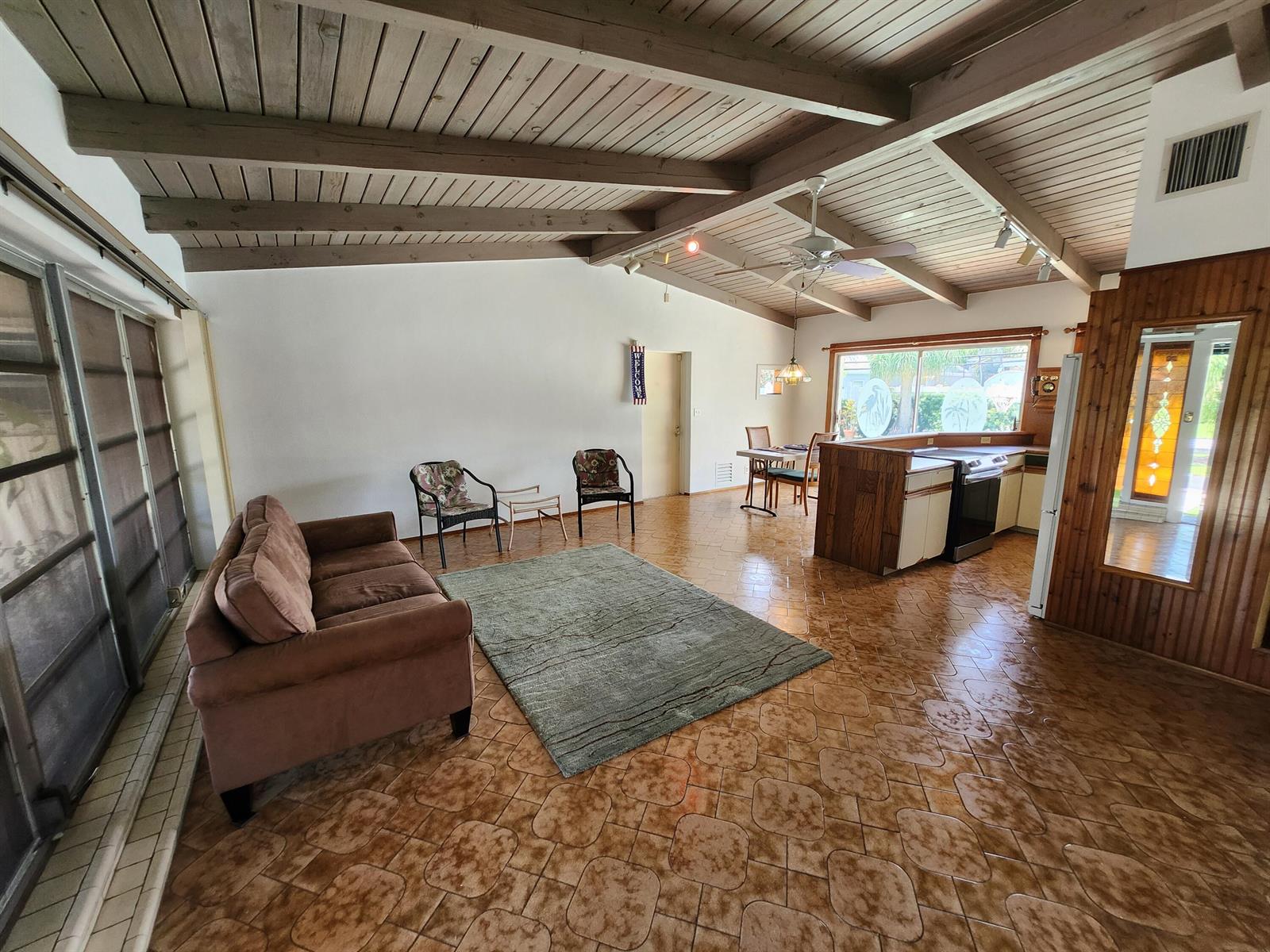A living room and kitchen area with vaulted wood-beam ceilings and patterned tile flooring — 111 SE 7th Street, Pompano Beach FL 33060, POMPANO BEACH, FL