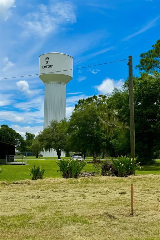 A tall white water tower stands in a grassy field under a blue sky — 1205-1209 W ALEXANDER STREET, PLANT CITY, FL