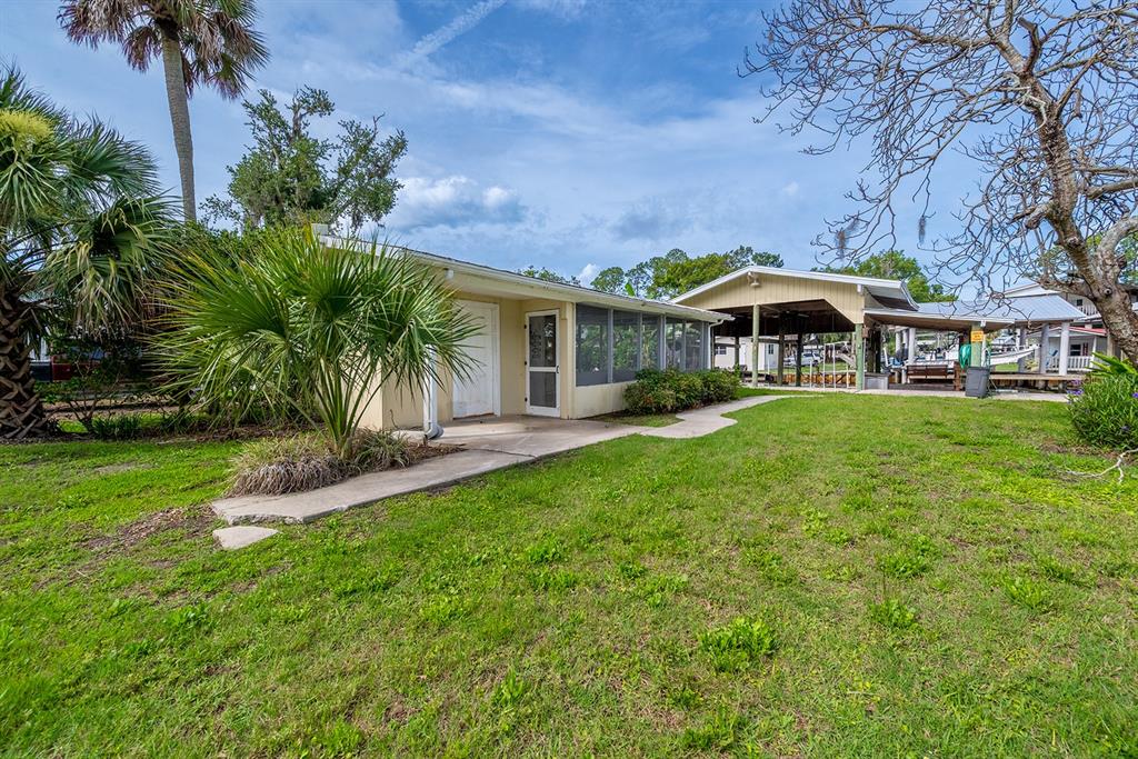 A single-story house with a screened porch and adjacent covered boat dock on a grassy lot — 192 SE 241ST STREET, SUWANNEE, FL