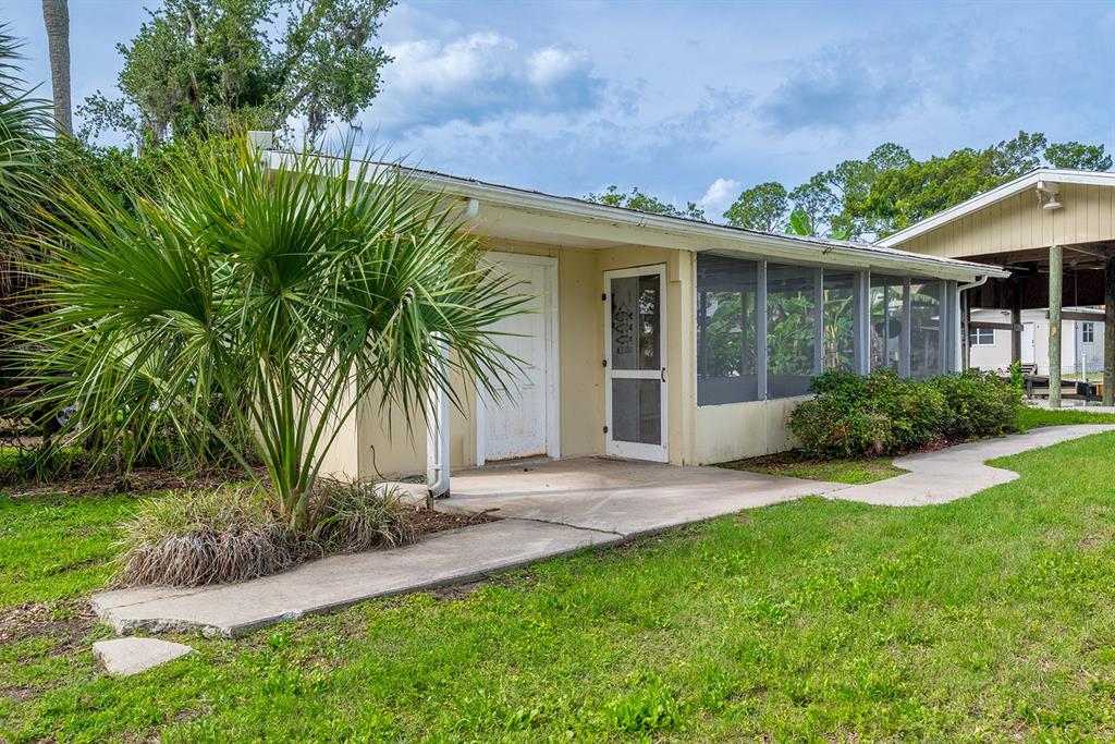 A small, light-colored house with a screened-in porch and a palm tree in the yard — 192 SE 241ST STREET, SUWANNEE, FL