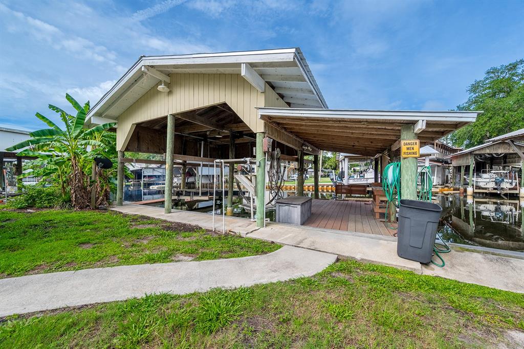 A covered boat dock with a wooden deck, boat lift, and a small storage bench — 192 SE 241ST STREET, SUWANNEE, FL