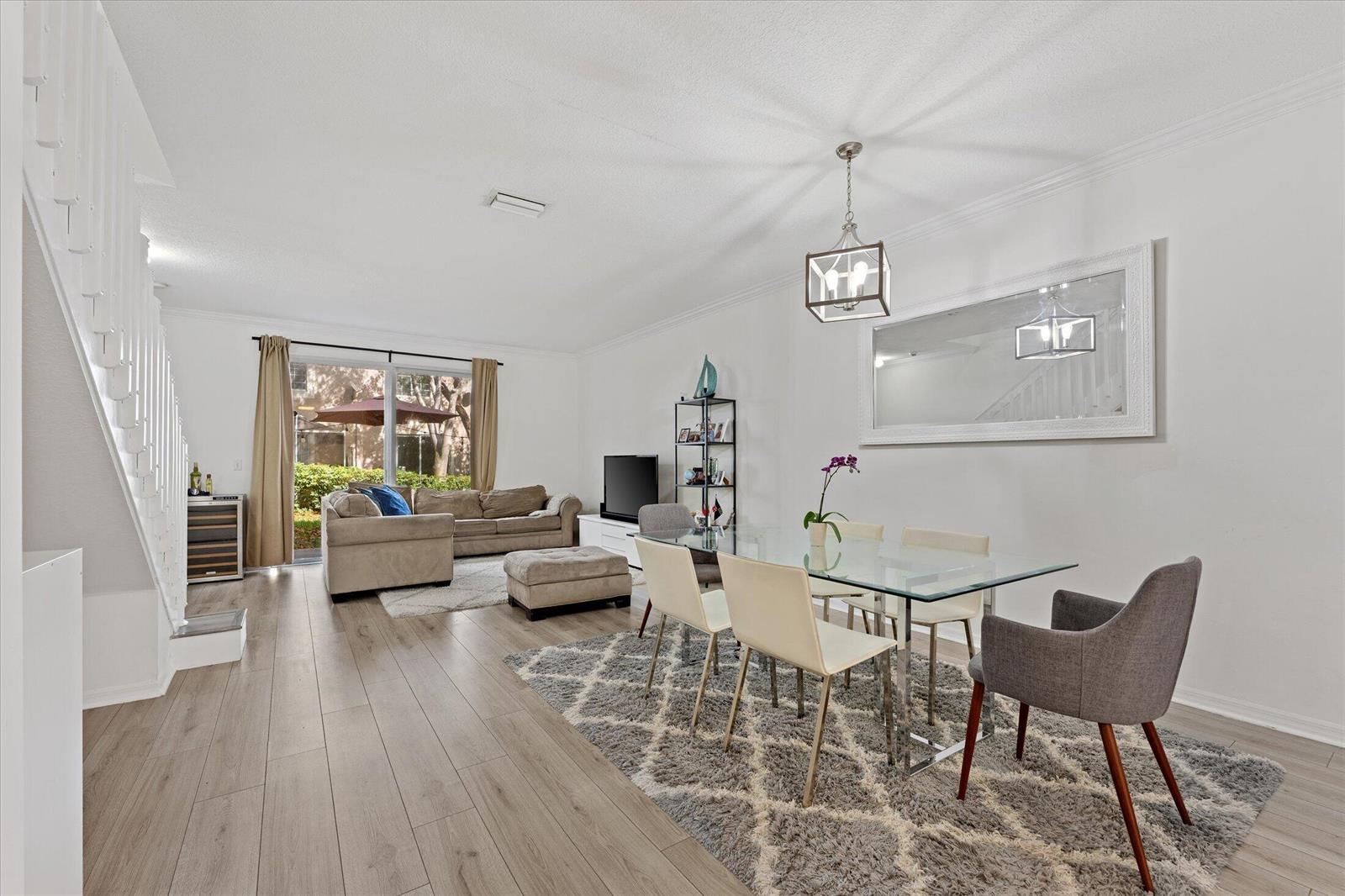 An open-concept living and dining area features light wood flooring, a glass table, and stairs — 2264 Salerno Circle, Weston FL 33327, WESTON, FL