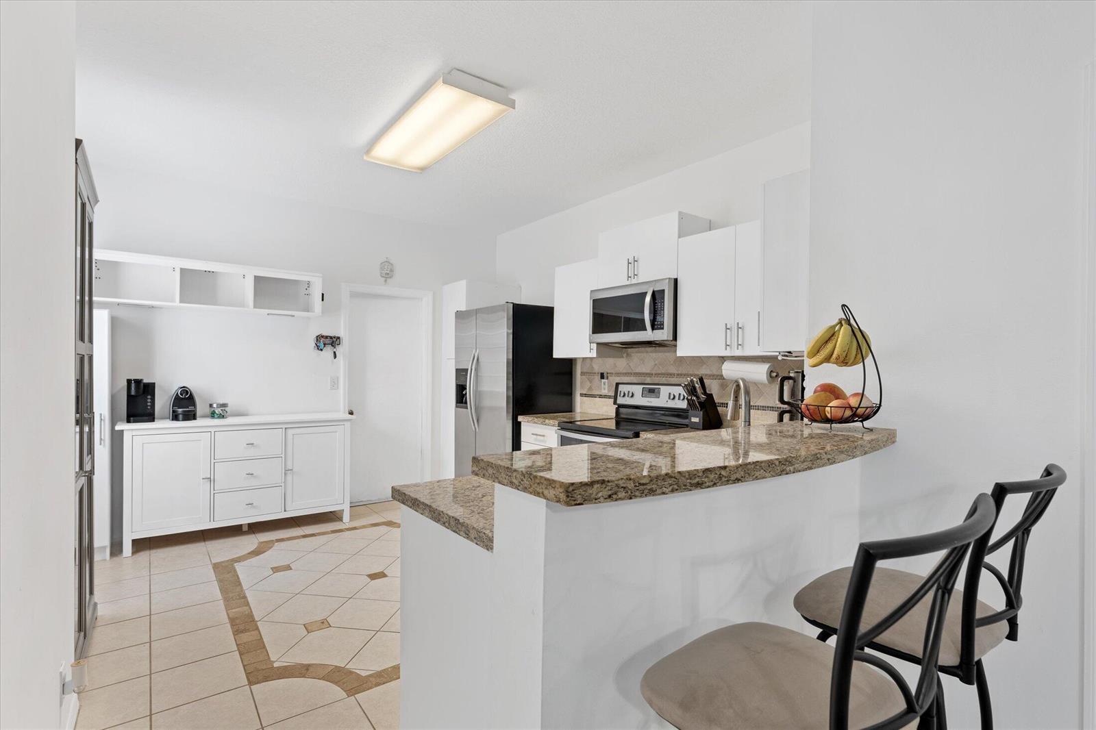 A kitchen features white cabinets, granite countertops, a breakfast bar, and tile flooring — 2264 Salerno Circle, Weston FL 33327, WESTON, FL