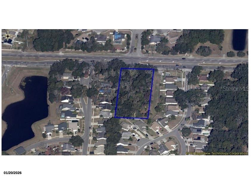 An aerial view shows a rectangular, wooded vacant lot outlined in blue within a neighborhood — CURRY FORD ROAD, ORLANDO, FL
