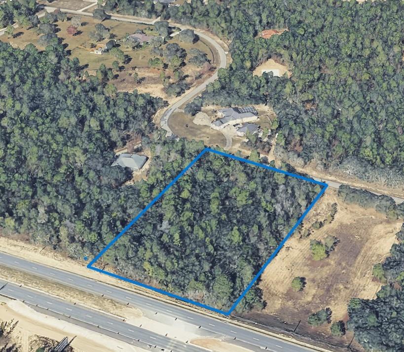 An aerial view shows a rectangular, wooded plot of land bordering a multi-lane highway — 5148 W DEPUTY DRIVE, BEVERLY HILLS, FL