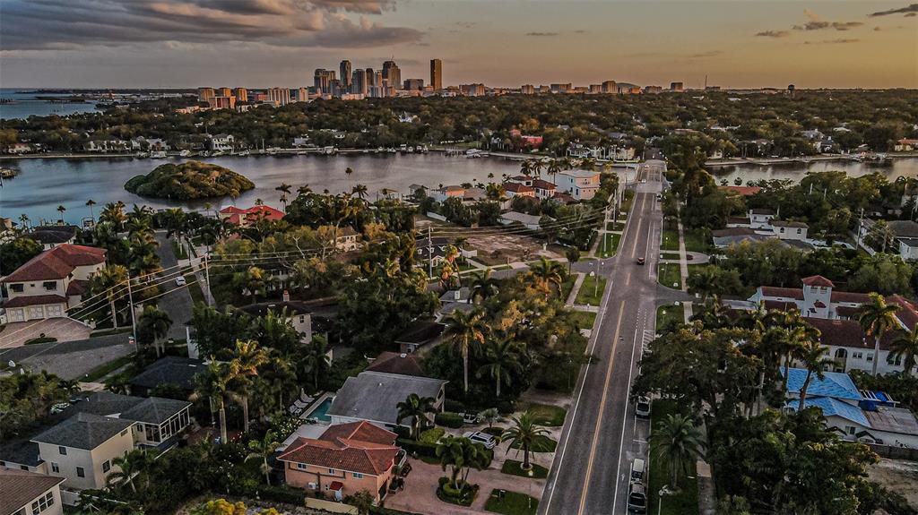 An aerial view of a residential neighborhood with a road leading toward a distant city skyline — 243 SNELL ISLE BOULEVARD NE, ST PETERSBURG, FL
