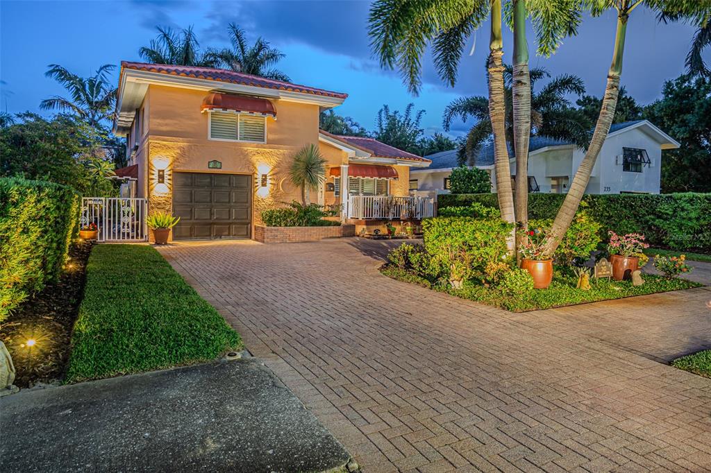 A two-story house with a paved driveway, palm trees, and a garage at dusk — 243 SNELL ISLE BOULEVARD NE, ST PETERSBURG, FL
