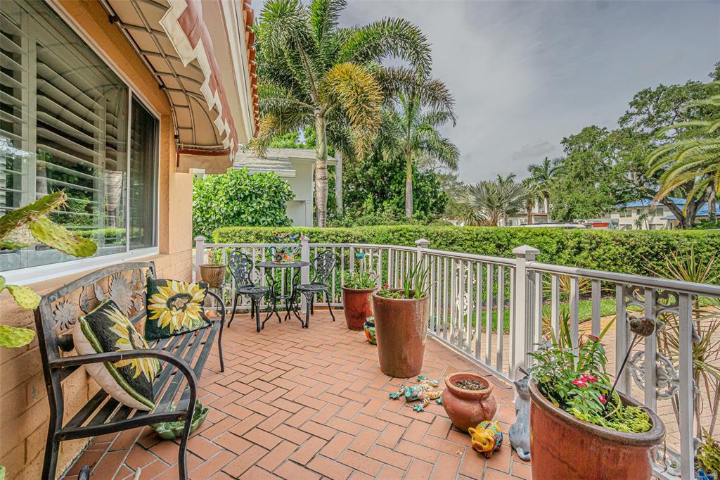 A brick-paved patio features a metal bench, bistro set, and potted plants behind a railing — 243 SNELL ISLE BOULEVARD NE, ST PETERSBURG, FL