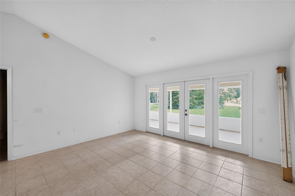 An empty room with white walls, tile flooring, and glass doors leading to a patio — 19735 SW 93RD PLACE, DUNNELLON, FL