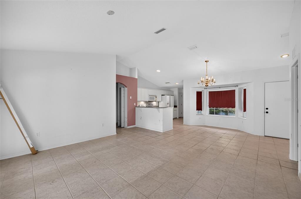 An open-concept living area features tile flooring, a kitchen with white cabinets, and a chandelier — 19735 SW 93RD PLACE, DUNNELLON, FL