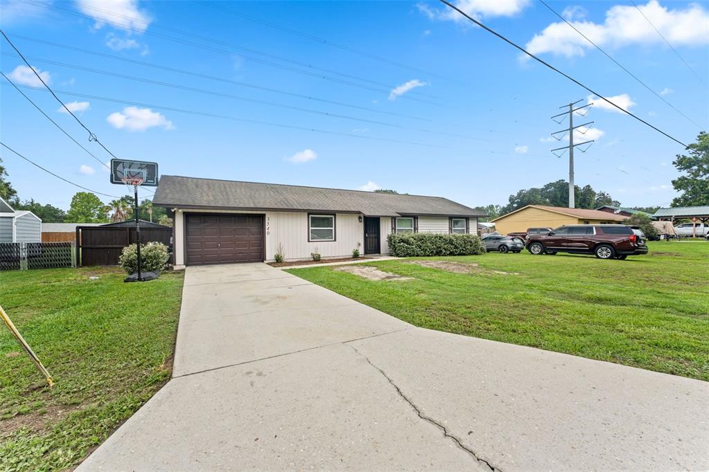 A single-story house with a brown garage door, concrete driveway, and a large grassy yard — 3540 NE 29TH TERRACE, OCALA, FL