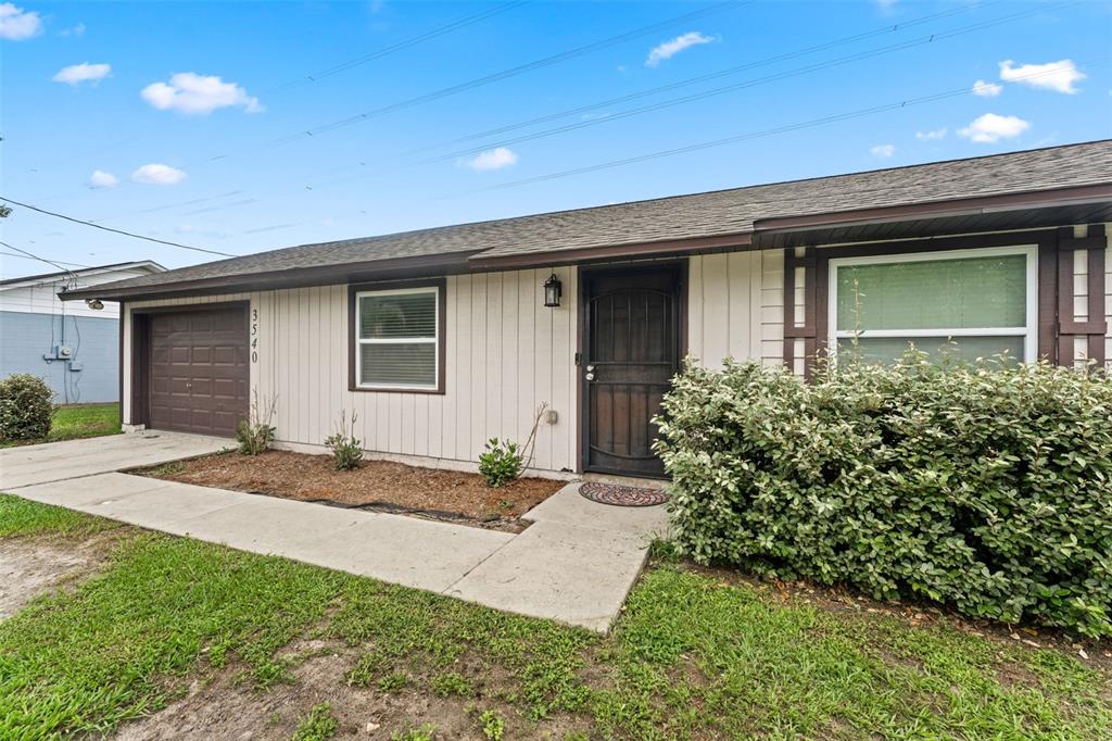 A single-story house with a brown garage door, light siding, and a large front bush — 3540 NE 29TH TERRACE, OCALA, FL
