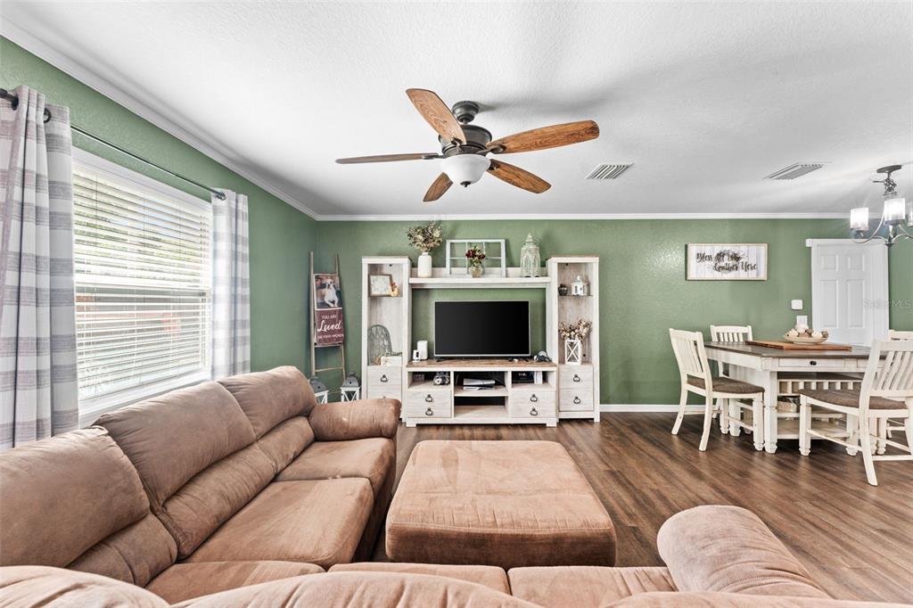 A living room with a brown sectional, wooden entertainment center, and dining area on green walls — 3540 NE 29TH TERRACE, OCALA, FL