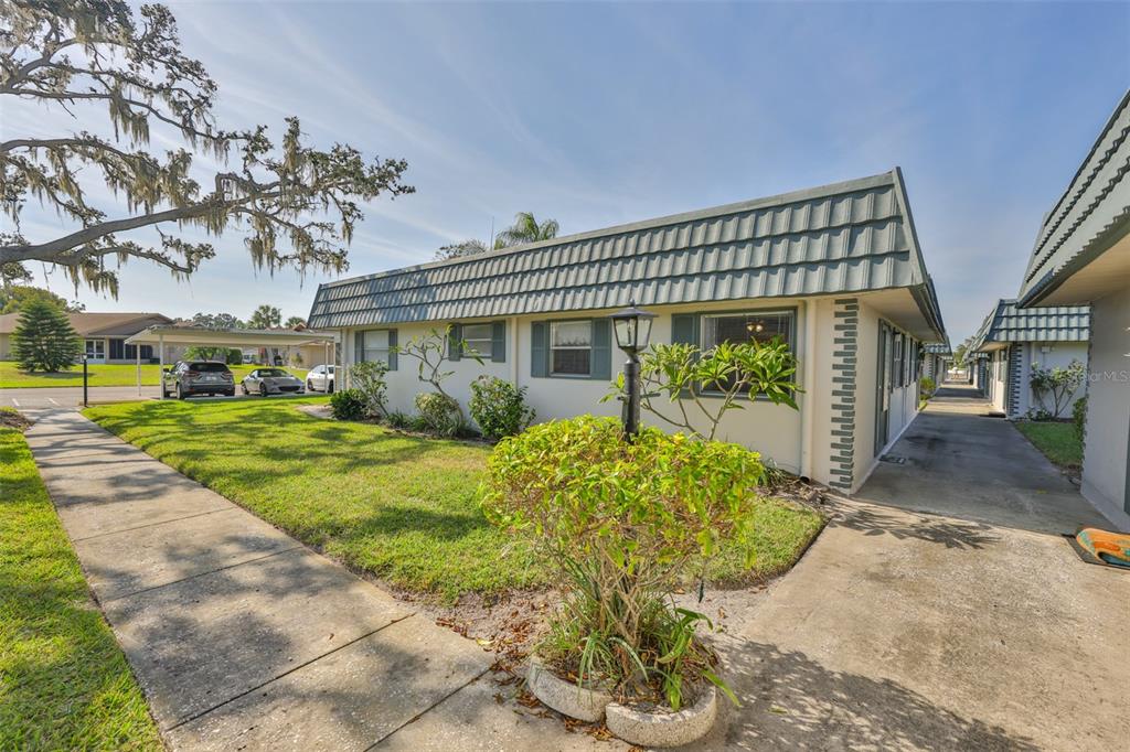 A single-story residential building with a mansard roof, a front lawn, and a concrete walkway — 1811 BEDFORD LANE UNIT 153, SUN CITY CENTER, FL