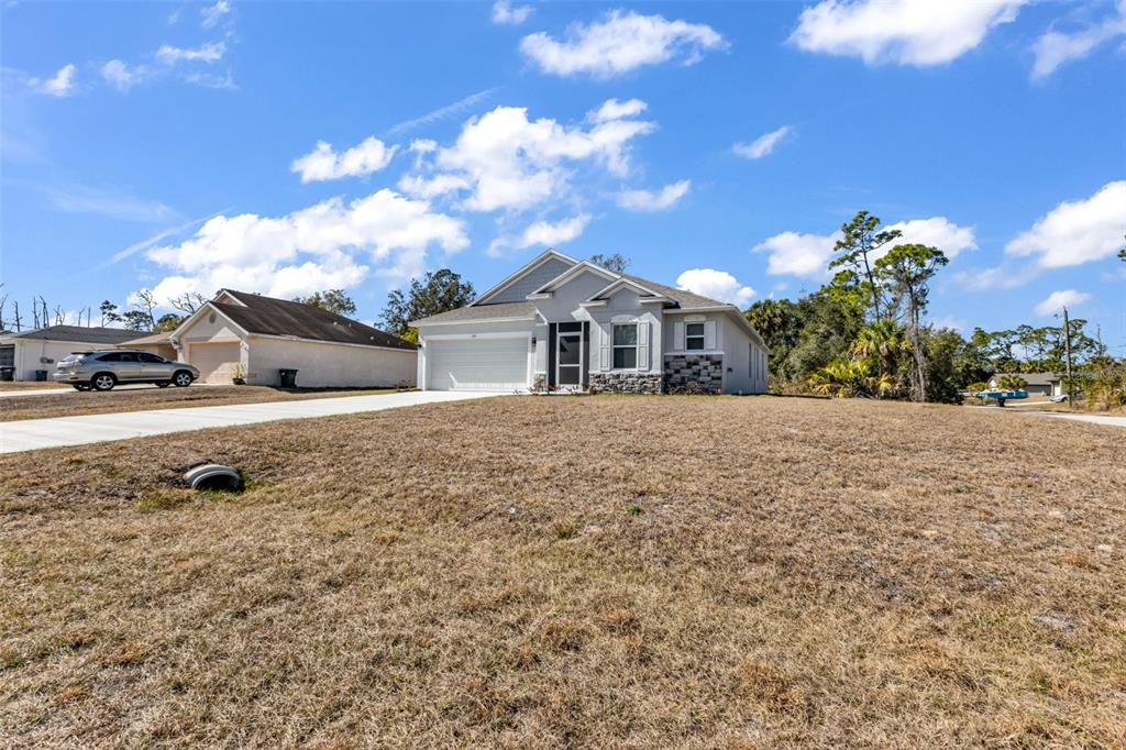 A single-story house with a white garage and stone accents sits on a grassy lot — 1111 S MCDUFF STREET, NORTH PORT, FL