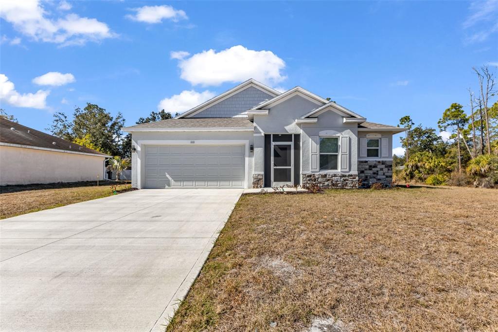 A single-story house with a two-car garage, stone accents, and a concrete driveway — 1111 S MCDUFF STREET, NORTH PORT, FL
