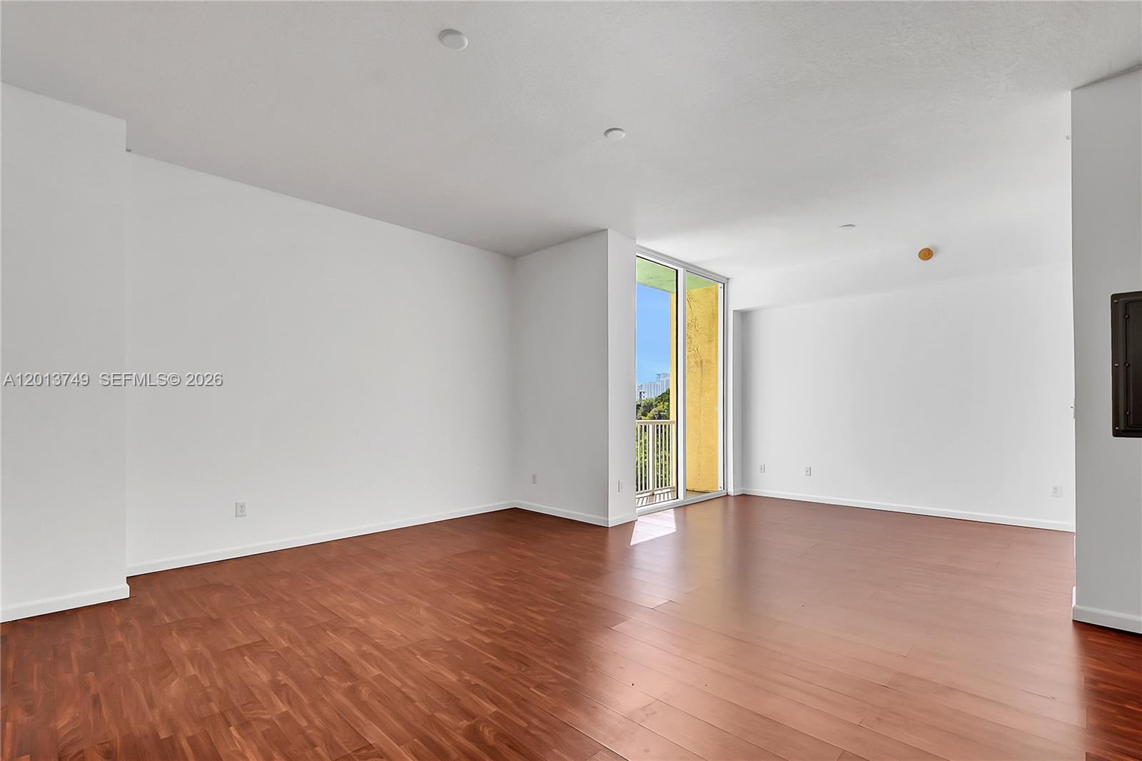 An empty room with white walls, dark wood flooring, and a sliding glass door balcony — 1350 NW 8th Ct # 4, Miami FL 33136, MIAMI, FL