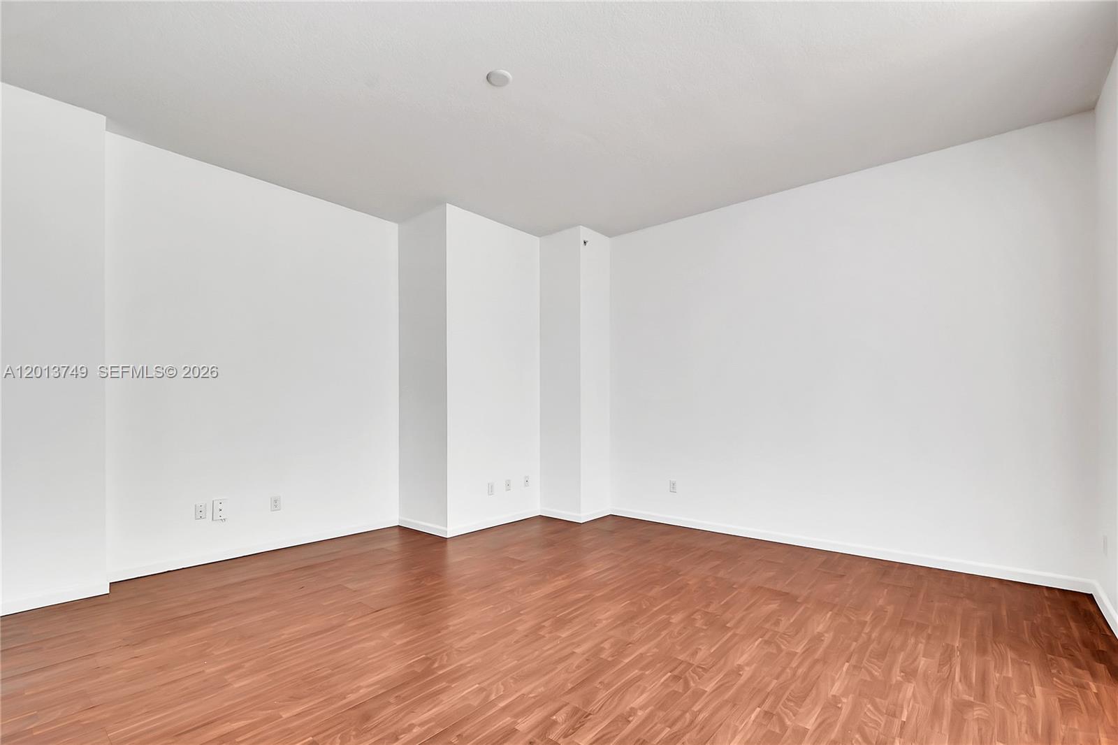 An empty room features white walls, wood-look flooring, and a prominent structural column — 1350 NW 8th Ct # 4, Miami FL 33136, MIAMI, FL