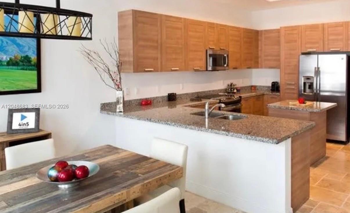 A kitchen with light wood cabinets, granite countertops, and a dining table in the foreground — 5184 NW 84th Ave, Doral FL 33166, DORAL, FL