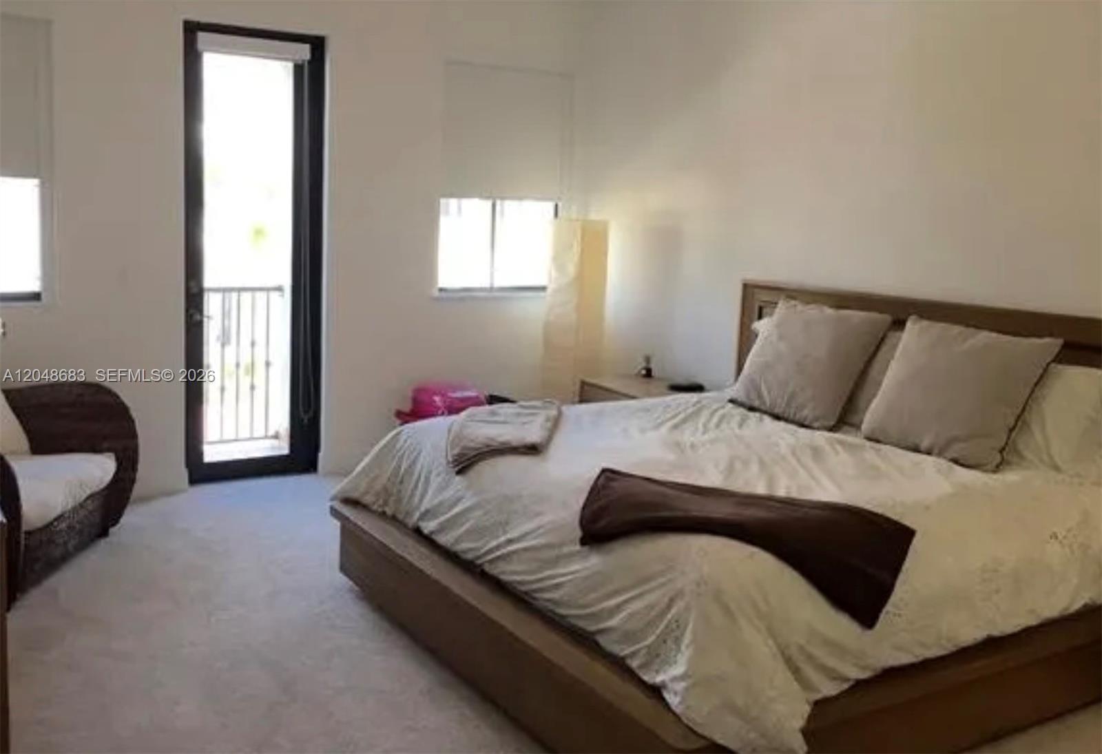 A bedroom features a platform bed, a wicker chair, and a door leading to a balcony — 5184 NW 84th Ave, Doral FL 33166, DORAL, FL