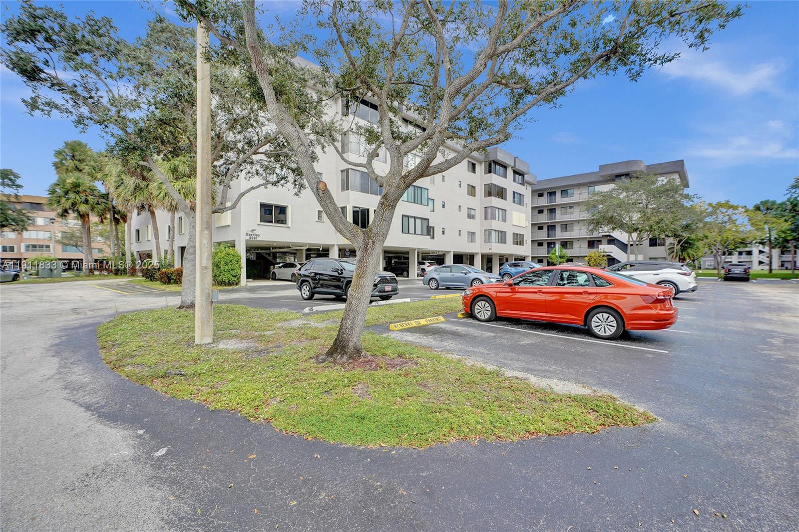 A multi-story apartment building with a parking lot and trees in the foreground — 8010 Hampton Blvd # 211, North Lauderdale FL 33068, NORTH LAUDERDALE, FL