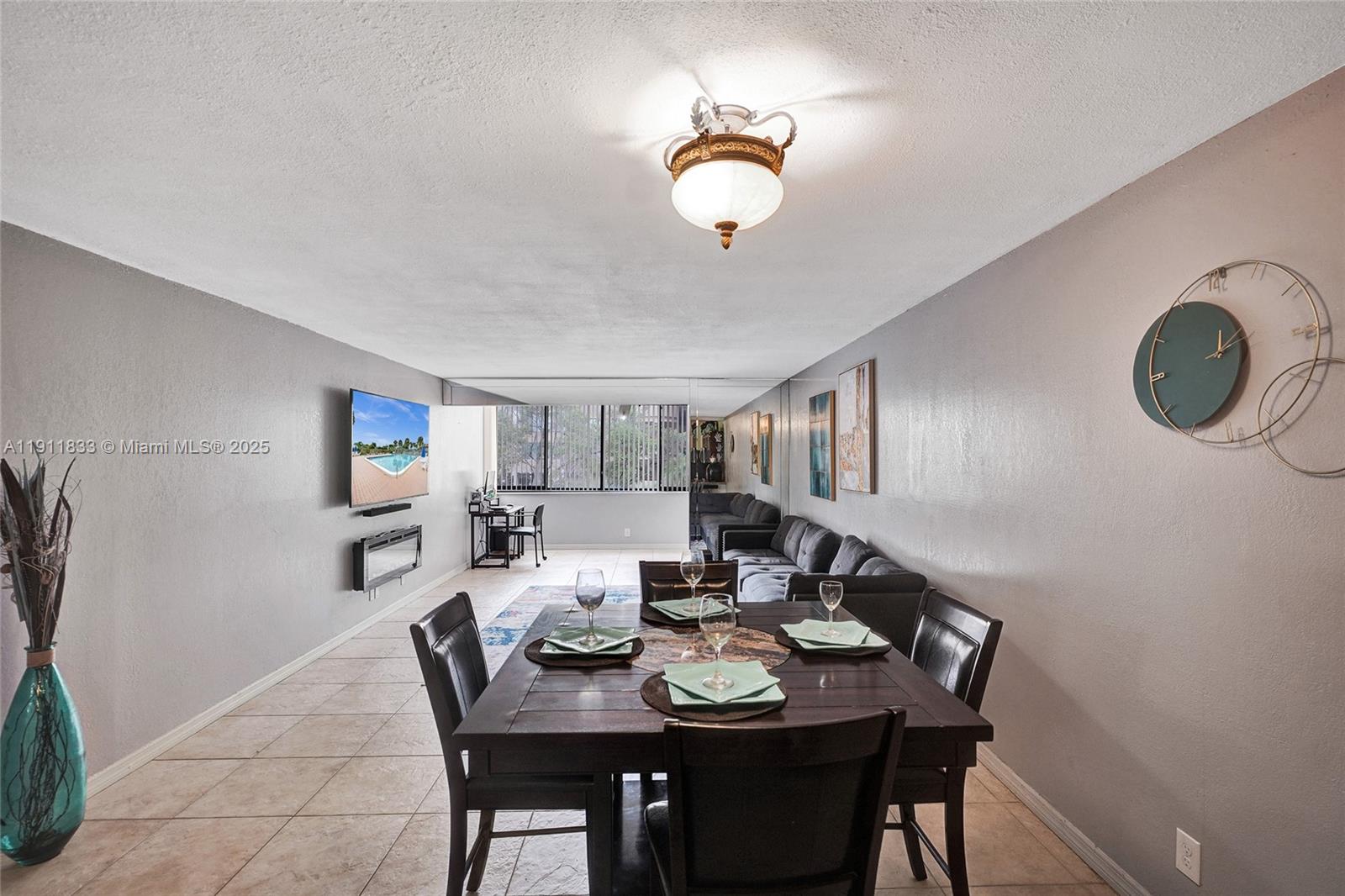 A dining area with a dark wood table sits before a living room with gray walls — 8010 Hampton Blvd # 211, North Lauderdale FL 33068, NORTH LAUDERDALE, FL