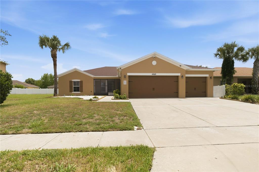 A single-story house with a tan exterior, a three-car garage, and a screened front entryway — 4069 MARINA ISLE DRIVE, KISSIMMEE, FL