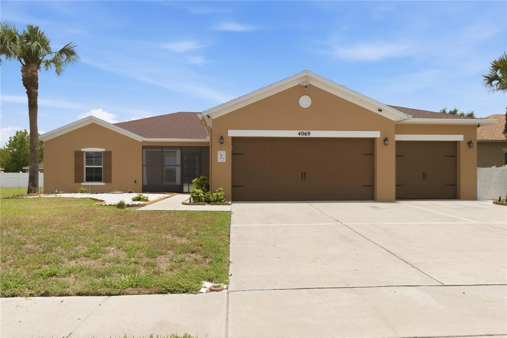 A tan single-story house with a three-car garage and a screened-in front entryway — 4069 MARINA ISLE DRIVE, KISSIMMEE, FL