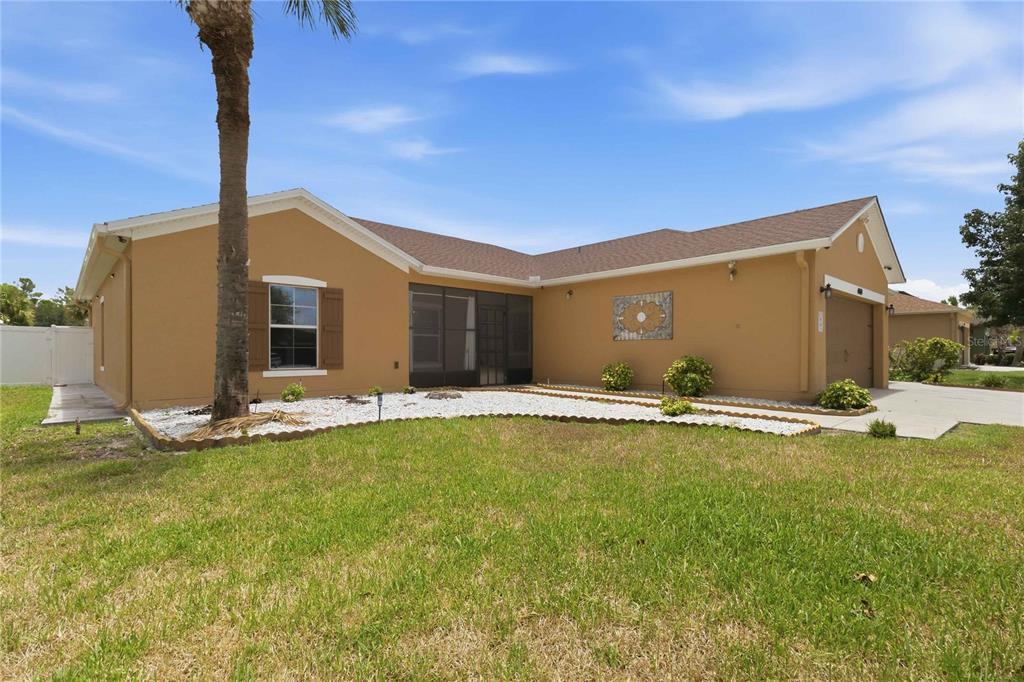 A single-story tan house with a screened-in porch, a two-car garage, and a lawn — 4069 MARINA ISLE DRIVE, KISSIMMEE, FL