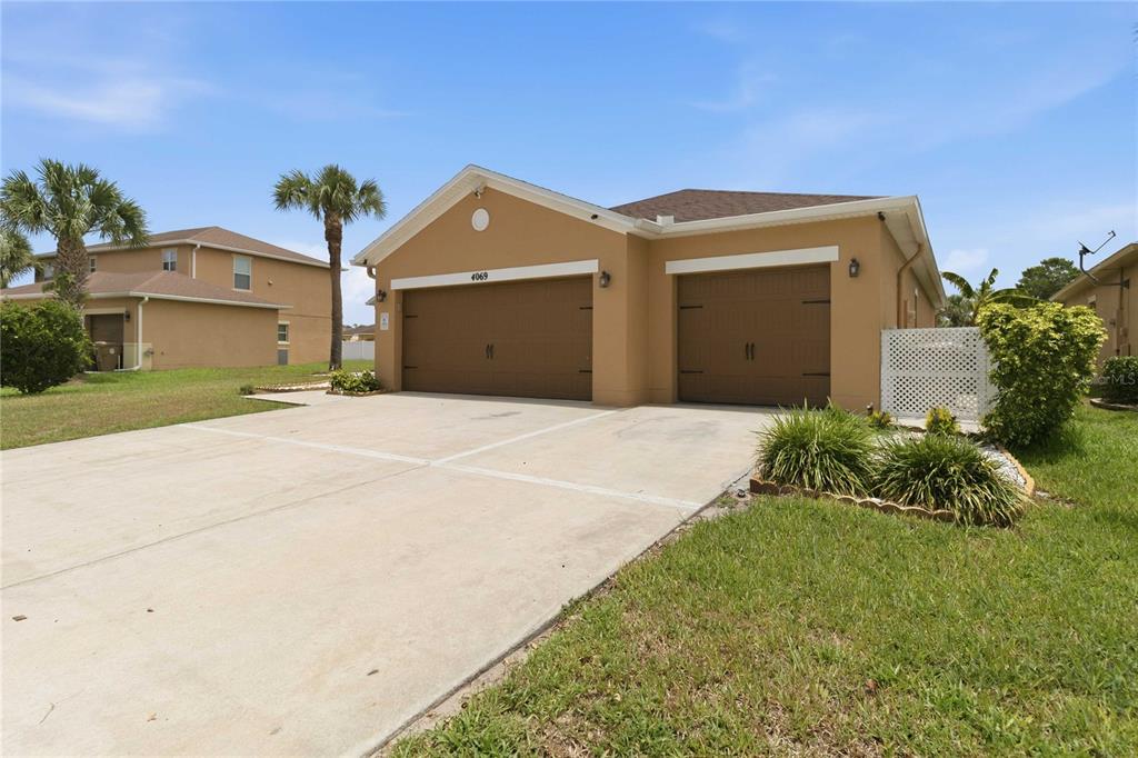 A tan, single-story house with a three-car garage and a concrete driveway — 4069 MARINA ISLE DRIVE, KISSIMMEE, FL