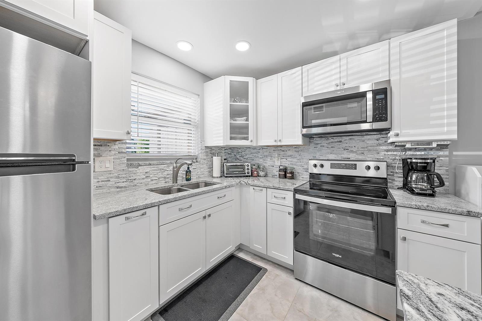 A kitchen with white cabinets, stainless steel appliances, and granite countertops — 725 Lori Drive # 111, Palm Springs FL 33461, PALM SPRINGS, FL