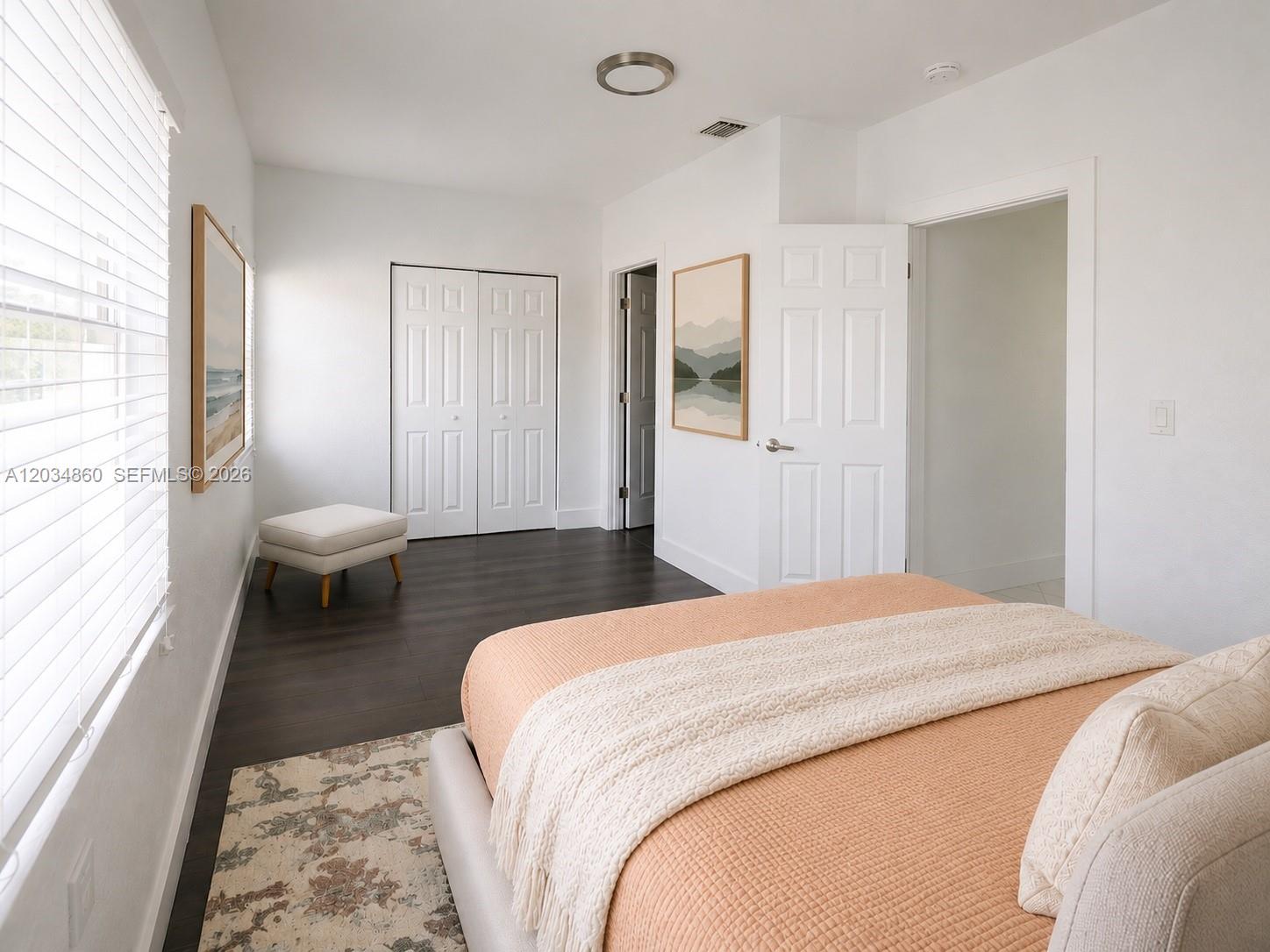 A bedroom features a peach-colored bed, dark wood flooring, white walls, and two doorways — 2272 NW 2nd St # 2, Miami FL 33125, MIAMI, FL