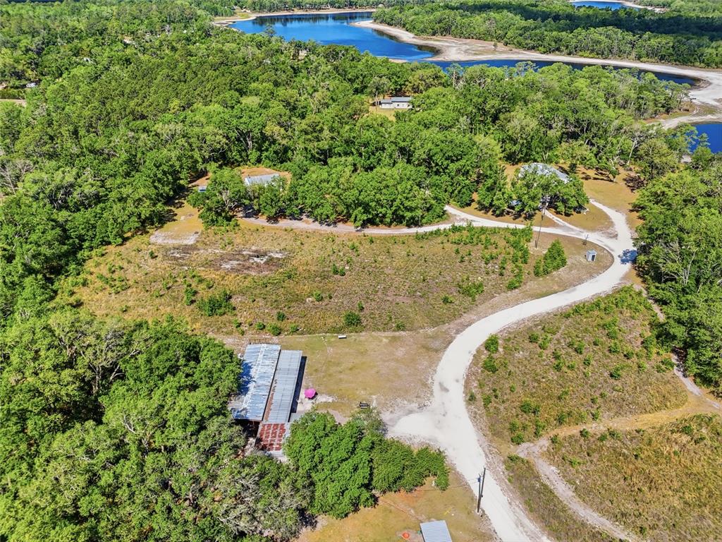 An aerial view shows a rural property with a metal-roofed barn, dirt driveways, and trees — 401 SE FALCON ROAD, BRANFORD, FL